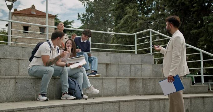Students attending an outdoor class and interacting with their professor. They receive assistance with tasks as needed.