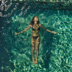 Fototapeten young woman in a bikini lies on the water with her arms outstretched and relaxes © Anita