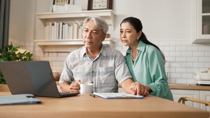 Obraz premium Grandmother comforting and supporting grandfather while looking at laptop show successful project and getting promotion. Happy senior businessman receive good news and talking to his wife. Myrmidon.