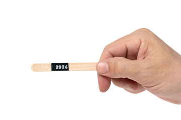 Hand holding wooden stick with inscription 2026.