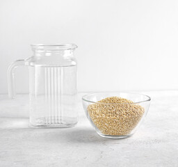 Quinoa seed in glass bowl and water in jug near to wash away the bitterness , organic food for...
