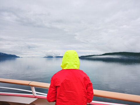 tourist wearing a red and yellow parka on a cruise in Alaska. 