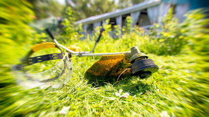 Lawn trimmer on a green lawn in front of the house