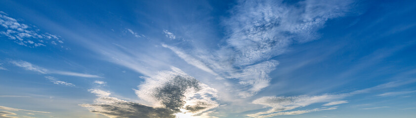 Blue sky with a few clouds and a sun shining through them