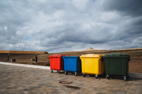 A vibrant and visually appealing row of colorful trash cans lines the busy sidewalk, creating an eyecatching and lively scene that attracts many pedestrians and curious passersby alike