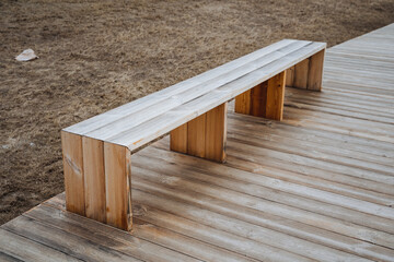 A beautifully crafted wooden bench is comfortably resting on a sturdy wooden deck, which provides a perfect and inviting spot to relax, unwind, and enjoy the beauty of nature outdoors