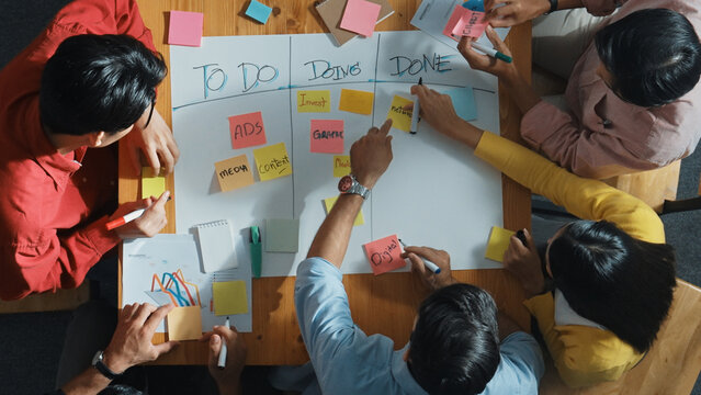 Top view of people writing and making scrum task board while writing marketing and planning strategy at colorful sticky notes. Smart team manage work performance by using kanaban board. Convocation.