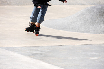 Part of the silhouette of an unrecognizable girl practicing inline skating in park mode on a track