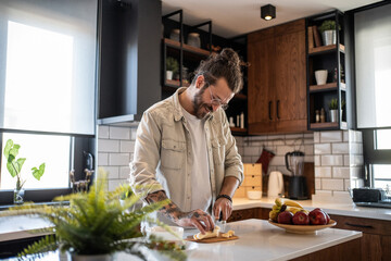 Tattooed man cutting banana on kitchen counter