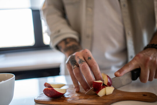 Chef cutting red apples on wooden board in modern kitchen