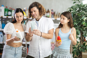 Glad family in summer clothes deciding which sunscreen to buy in supermarket