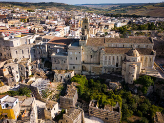 Scenic view of Gravina in Puglia, Italy, showcasing historic stone architecture, the iconic Roman bridge over the ravine, and the picturesque old town under a clear blue sky.