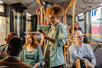 Young woman using smartphone while standing on a moving bus © PintoArt