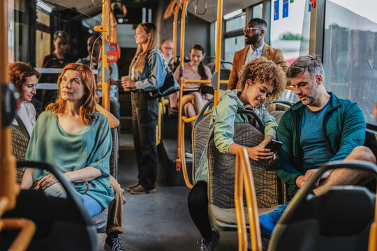 Passengers using mobile phone and riding on city bus