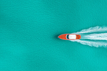 A stunning aerial view of a speed boat cutting through the turquoise ocean, leaving a white foamy