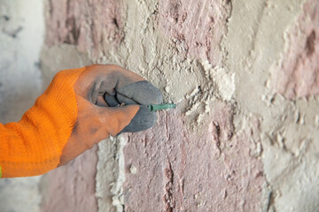 Worker installing a plastic anchor into a wall.