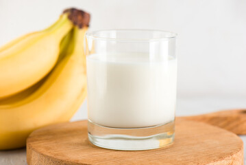 Banana milk in a glass on a wooden board, closeup. Traditional Korean drink.