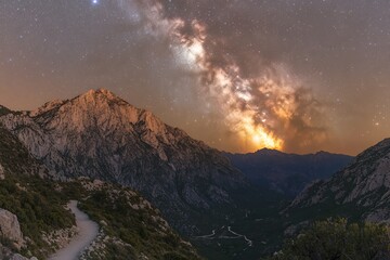 A high mountain pass with visible paths under a starlit sky and a bright moon.