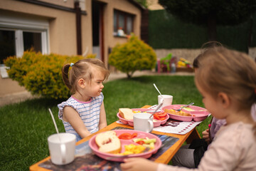 Children enjoy a sunny breakfast in a lush garden setting