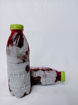 Bottles of frozen hibiscus leaf drink on white background. Homemade bottled and chilled sobolo drink with frost or ice crystals around bottle. Refrigerated hibiscus drink in plastic bottle.