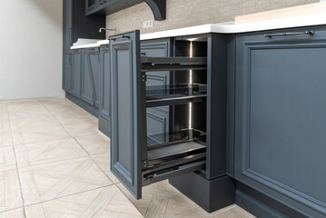 Open deep drawer in a classic dark blue kitchen interior