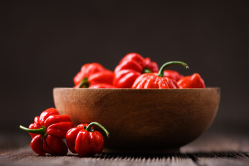 Wooden bowl filled with ripened red habanero peppers (capsicum chinense) on rustic table. Very hot...