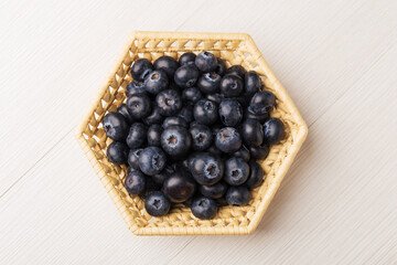 Blueberry in wicker basket on white wooden background. Top view.