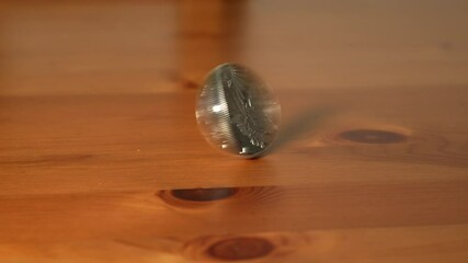 Close-Up of Hand Spinning American Silver Dollar Coin on Wooden Table - Powered by Adobe