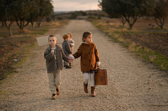 Boy and girl walking hand in hand along a rural road with a suitcase. A nostalgic scene of childhood, adventure, and friendship, evoking wanderlust and simple countryside life.
