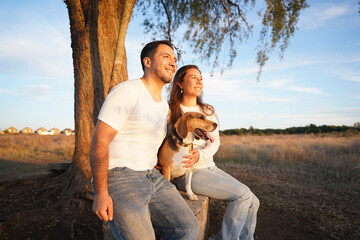 A loving couple Latin american along with their dog Beagle is happily enjoying a beautiful sunset...