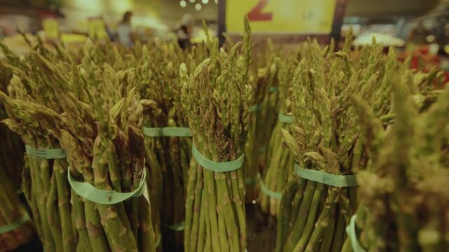 Fresh asparagus neatly bundled on a grocery store shelf, showcasing its vibrant green color and crisp texture in a well-lit retail environment