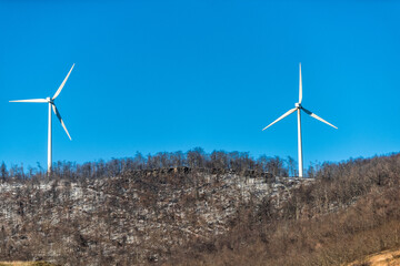 Two wind turbines in windmill farm on Appalachian mountain peak top in West Virginia Canaan valley scenic view in winter snow