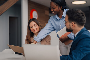 Businesswomen and businessman collaborating on project using laptop and documents