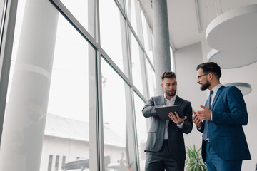 Businessmen discussing work using tablet in modern office building