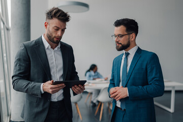 Businessmen using tablet and discussing work in modern office