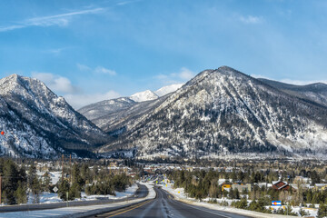 Frisco, Colorado snow capped rocky mountains peaks and cityscape in winter weather blue sky and houses buildings on street road to downtown