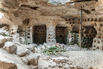 Historic rock-cut dovecote featuring numerous triangular nesting holes, carved into a cave-like structure, likely used for pigeon breeding. Hurvat Beit Loya, Israel