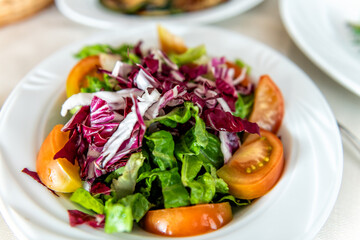 Sardinian plain mixed salad vegetables on table white plate in Sardinia with raddichio, lettuce and sliced tomatoes