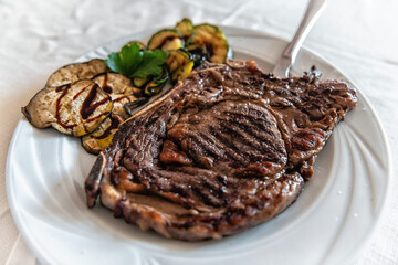 Local beef steak beefsteak plate Sardinian traditional dish in Sardinia macro closeup with grilled eggplant zucchini slices on side