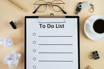 to do list on clipboard with office supplies, isolated on beige background