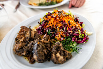 Wild boar pork meat morsels pieces in balsamic vinegar sauce Sardinian traditional dish in Sardinia with side salad of seeds