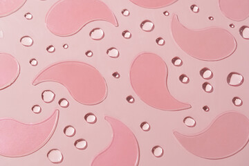 Patterned pink hydrogel eye patches on a pink backdrop with a textured drop effect. Crafted to hydrate and refresh the delicate under-eye skin. Skin care routines and rejuvenation concept.