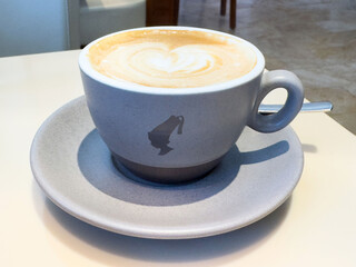 Close-up of heart latte art in grey cup on white table
