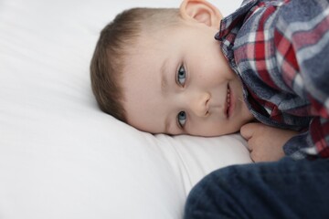 Cute little boy lying on bed at home