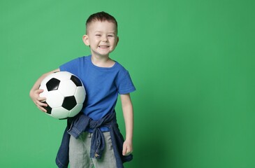 Cute little boy with soccer ball on green background, space for text