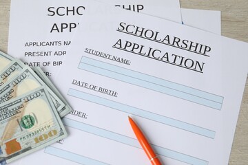 Obraz premium Scholarship application forms, pen and dollar banknotes on wooden table, above view