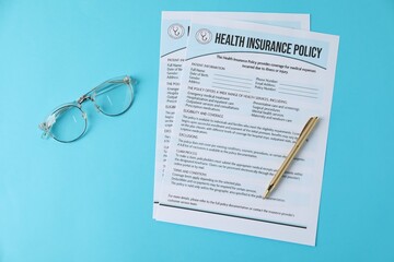 Health insurance policy forms, glasses and pen on light blue background, flat lay