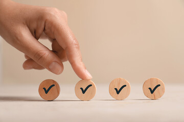 Approved. Woman touching wooden circle with check mark on beige background, closeup