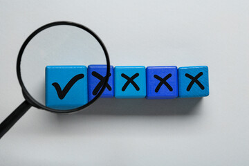 Approved. Cube with check mark among other ones with crosses, view through magnifying glass