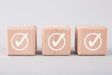 Approved. Wooden cubes with check marks on grey background, closeup